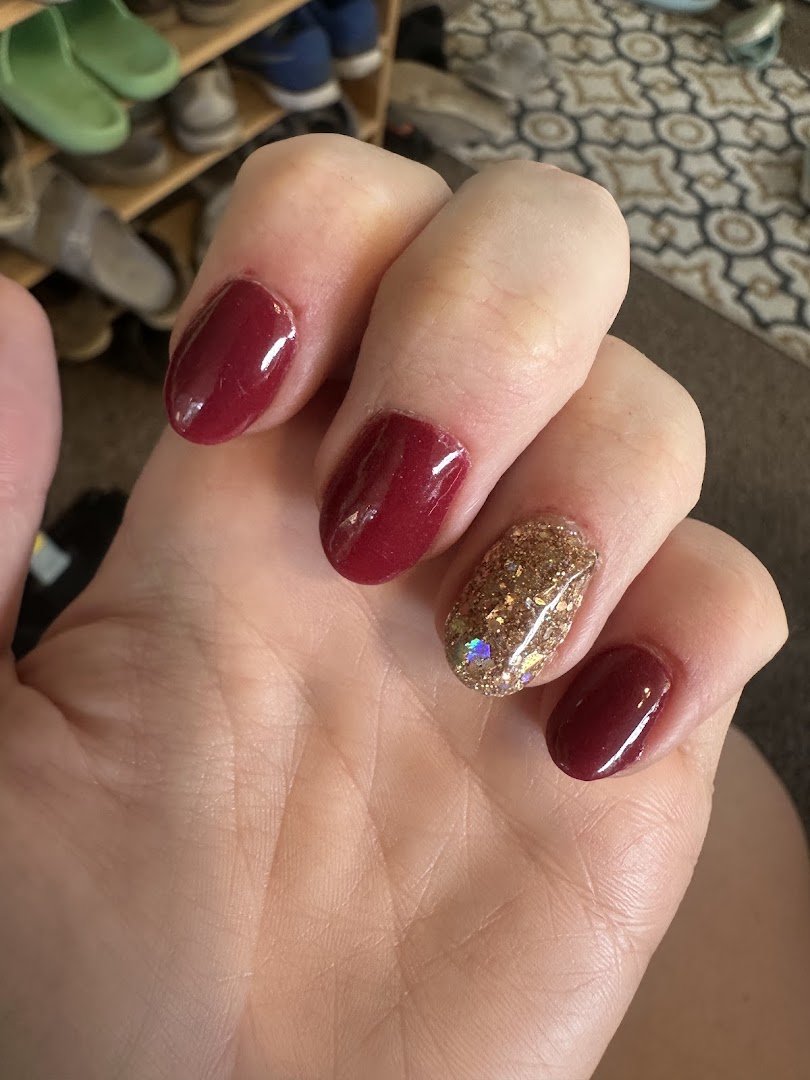 Nail technician shaping acrylic nails at a salon station.